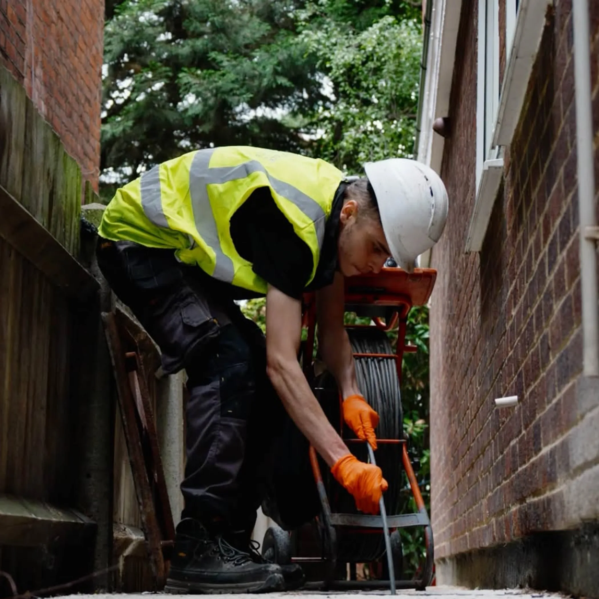 worker clearing outdoor drain grate